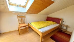 1 dormitorio pequeño con 1 cama y 1 silla en ANJA Seeblick Appartement ANJA Haus Hänsel u Gretel direkt am Ossiacher See mit Hallenbad, Skiarena Gerlitzen 