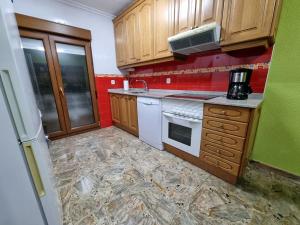 een kleine keuken met houten kasten en rode muren bij 126B Apto Playa - 3 Habitaciones in Gijón