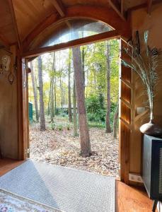 an open door in a cabin with a view of a forest at Pipowagen de Kat in de Hoge Kempen nabij Maastricht in Lanaken