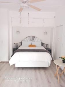 a white bedroom with a white bed and a table at Pythons Guest Lodge in Rustenburg