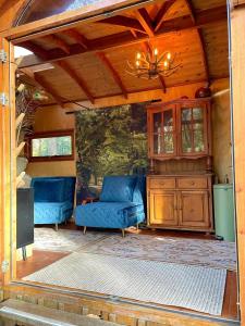 a porch with two blue couches and a chandelier at Pipowagen de Kat in de Hoge Kempen nabij Maastricht in Lanaken