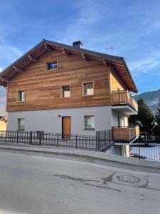 a large wooden house with a balcony on a street at La Casa di Armando in Bormio