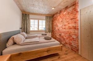 um quarto com uma cama contra uma parede de tijolos em Salzkristall - Ferienwohnung em Haus im Ennstal