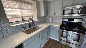a kitchen with white cabinets and a stove and a sink at Large Pool & Patio Cozy Single Story Family House in Las Vegas