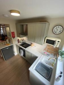 a kitchen with a sink and a clock on the wall at Wee Cottage - Super King bed! in Penpont
