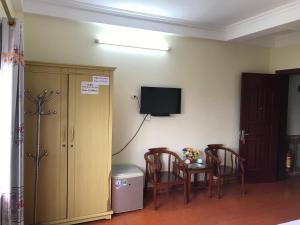 Zimmer mit 2 Stühlen, einem Tisch und einem TV an der Wand in der Unterkunft KHÁCH SẠN HÀ ANH 1 NỘI BÀI in Noi Bai