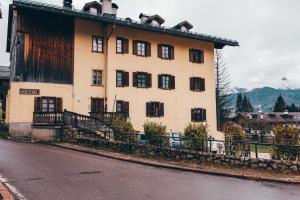 Un gran edificio blanco con ventanas negras en una calle. en Casa Da l Oio, en Cortina dʼAmpezzo
