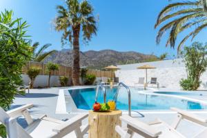 a pool with chairs and a fruit bowl on a table at Okeanis Mystique South in Ierapetra