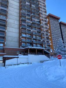 a snow covered street in front of a tall building at Chez Elodie au CORBIER in Le Corbier