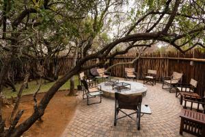 a patio with chairs and a table under a tree at The Citrine House 33 in Mabula