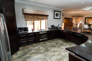 a kitchen with black cabinets and a tile floor at The Citrine House 33 in Mabula