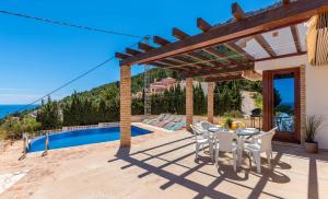 un patio con mesa y sillas junto a una piscina en Villa Anis - PlusHolidays, en Calpe