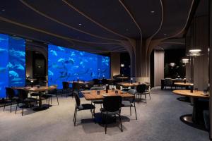 a restaurant with tables and chairs and a large aquarium at Resorts World Sentosa - Equarius Villas in Singapore