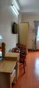 Habitación con sillas y TV en la pared. en Nhà nghỉ hà anh 2 nội bài, en Noi Bai