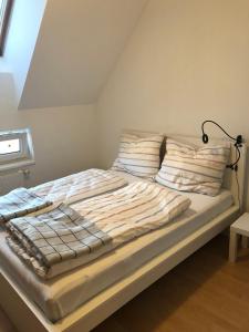 a bed with striped blankets and a lamp on it at MF City Apartment in Korneuburg