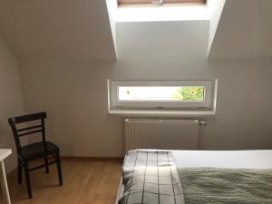 um quarto com uma cama, uma cadeira e uma janela em MF City Apartment em Korneuburg