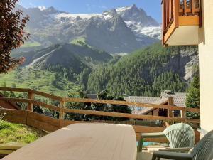 a table and chairs on a balcony with a view of mountains at Cosy Appart'Hotel - Panoramic Village - La Grave in La Grave