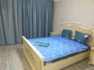 Schlafzimmer mit einem Bett mit blauer Bettwäsche und Kissen in der Unterkunft Отличная 3х комнатная квартира in Oral