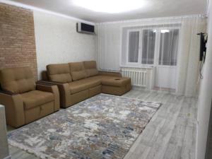 ein Wohnzimmer mit einem Sofa, Stühlen und einem Teppich in der Unterkunft Отличная 3х комнатная квартира in Oral
