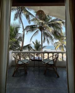 a balcony with chairs and a table and palm trees at Silent Beach Resort in Mandrem