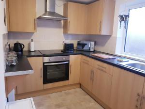 a kitchen with wooden cabinets and a stove top oven at The Birchington - 3 Bedroom Apartment & Workspace in Westoe