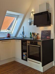 Il comprend une cuisine équipée d'une cuisinière et d'un four micro-ondes. dans l'établissement Luxuriöses Penthouse mit Dachterrasse & Massagesessel EM-APARTMENTS DEUTSCHLAND, à Bielefeld