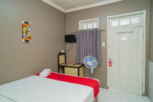 Cette chambre comprend un lit et une porte blanche. dans l'établissement RedDoorz at Oro Oro Ombo Batu, à Tlekung