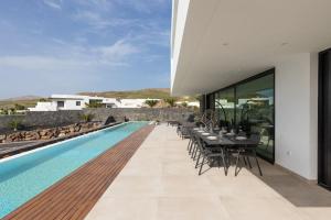 a pool with tables and chairs next to a house at BAMANIJA by Buenavilla in Puerto Calero