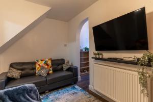 a living room with a black couch and a flat screen tv at "Furnished Rentals Direct" DominionHouse cul-de-sac Home for 6 people in Anfield near LFC, Goodison Park, Free Street Parking, Suits Travellers, contractors and Family, Near Football action and 10 minutes drive to Liverpool City Centre in Liverpool