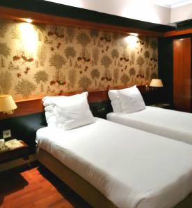 two beds in a hotel room with white sheets at Hotel Lara in Valença