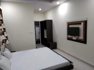 a bedroom with a bed and a tv on the wall at Hotel Shree Hari in Deoghar