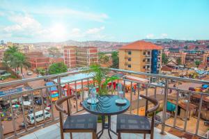 balcón con mesa, sillas y ciudad en Bukandula Hotel en Kampala