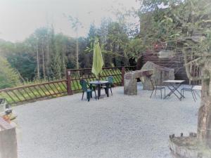 a patio with a table and chairs and an umbrella at The House in the Woods in Plélauff