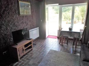 a living room with a television and a table with chairs at The House in the Woods in Plélauff