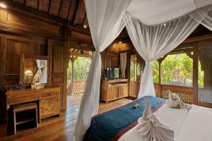 a bedroom with a bed and a desk and a television at Kawan Antique Ubud Villa in Ubud