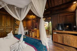 a bedroom with a bed and a television in a room at Kawan Antique Ubud Villa in Ubud