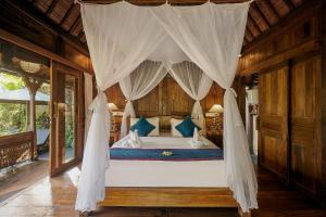 ein Schlafzimmer mit einem Himmelbett mit blauen Kissen in der Unterkunft Kawan Antique Ubud Villa in Ubud + 64 Fotos