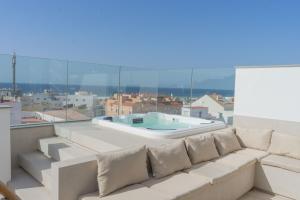 a white couch on a balcony with a bath tub at Poniente - Ático Exclusivo con jacuzzi parking in Tarifa
