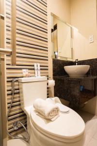 a bathroom with a white toilet and a sink at West Loch Park Hotel Vigan in Vigan