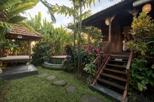 a small house with a staircase in a garden at Kawan Antique Ubud Villa in Ubud