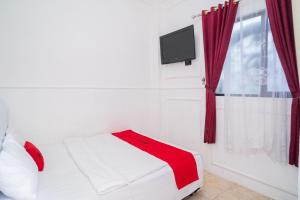 a bedroom with a bed and a tv and a window at RedDoorz Syariah at Aura Homestay in Ponorogo