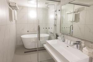 a bathroom with a sink and a tub and a mirror at Hotel Rose Garden Shinjuku in Tokyo