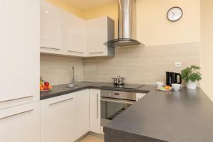 a kitchen with white cabinets and a clock on the wall at Czapelska Apartment Warsaw Praga Południe in Warsaw