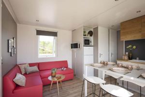 een woonkamer met een rode bank en een tafel bij MAS DES LAVANDES in Sérignan