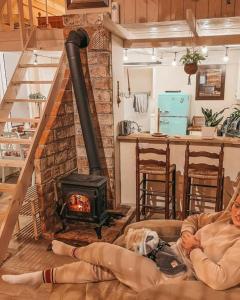 a man sitting on a couch in a living room with a stove at Ojcowski Zakątek-uroczy domek do wynajęcia in Wola Kalinowska