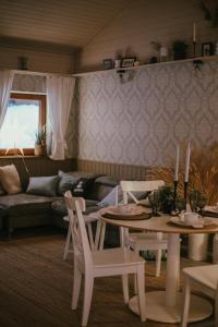 uma sala de estar com uma mesa e cadeiras e um sofá em VIESU MĀJA KALNARUŠĶI em Lūšakrogs