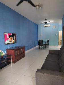 Una sala de estar con un sofá y un televisor. en Ruzimas Desaru Homestay, en Bandar Penawar