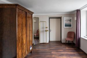 a hallway with a large wooden cabinet and two chairs at numa I Sonate Apartments in Salzburg
