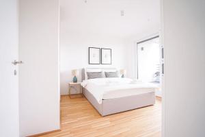 1 dormitorio blanco con 1 cama blanca y suelo de madera en Bright & Wonderful Apartment at Oberlaa Therme, en Viena