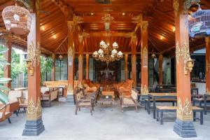 un'ampia hall con lampadario a braccio, tavoli e sedie di Griya Mataram Kotagede Mitra RedDoorz a Yogyakarta